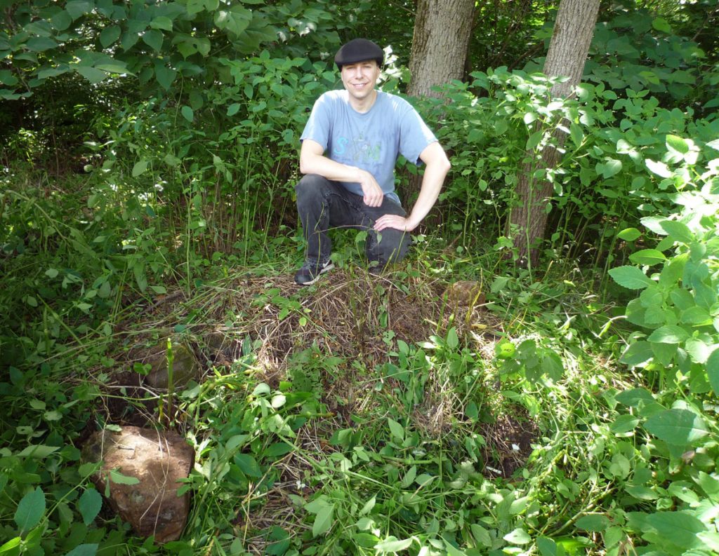 Andrew Hagenbuch in a field with stone